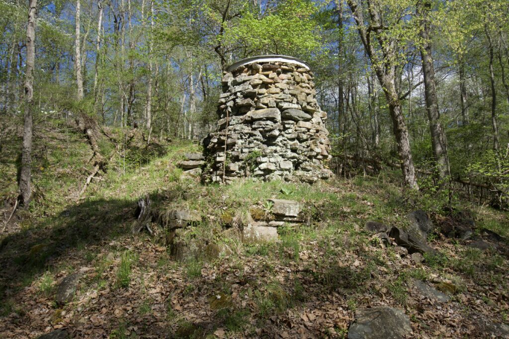 A stone tower-like structure on a hill in the woods